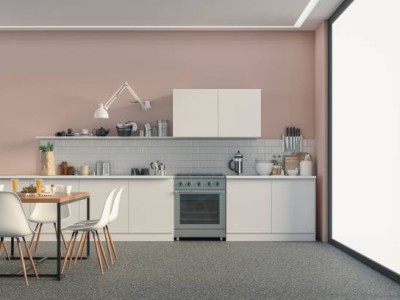 Empty modern kitchen with white wooden kitchen cabinets on a powder pink colored plaster wall background, partly white metro tiled wall, full dining table, and white chairs. Large windows on a side of the gray terrazzo floor with copy space. The retro style of the '70s. 3D rendered image.